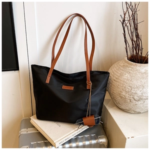 Vista dettagliata della borsa tote in nylon nero con manici in pelle marrone in interni