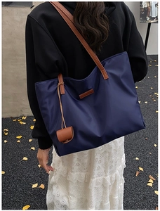 Dettaglio della borsa tote in nylon blu navy con manici e ciondolo in pelle marrone