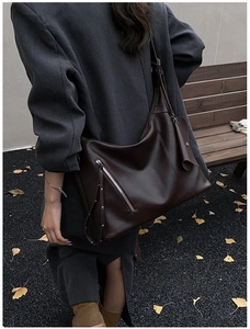 Detail of dark brown leather tote bag with metallic zipper and decorative small pouch