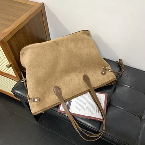 Close-up of brown suede tote bag with leather straps and gold metal ring details