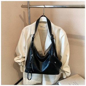 Detail of a black hobo shoulder bag in high-quality leather texture on a white blazer