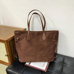Detailed close-up of dark brown suede tote bag featuring side metal buckle and leather handle