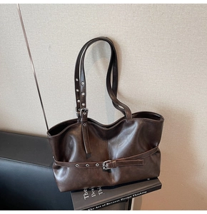 Detailansicht der dunkelbraunen Vintage-Tote-Bag mit Metallschnallen auf Büchern