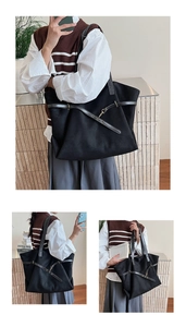 Close-up of black suede tote bag showing thin leather straps and metallic buckle detail