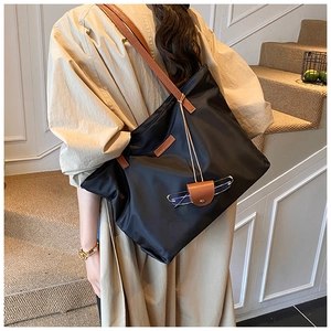 Dettaglio della borsa tote in nylon nero con finiture in pelle e gancio portaocchiali utile