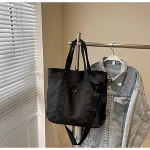 Detail of black canvas tote bag with metal snap pocket on clothes hanger