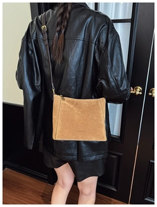 Detail view of brown suede shoulder bag with gold hardware and brand logo on leather