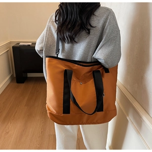 Rear view of a large orange canvas tote bag showing adjustable black strap and capacity
