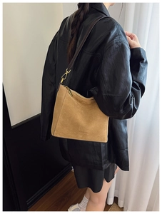 Detail of the suede tote bag showing the embossed brand logo and premium brown leather strap