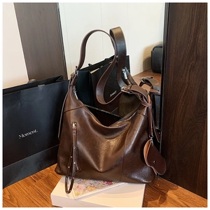 Detail of dark brown hobo bag featuring oily leather texture and heart pouch attachment