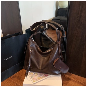 Detail view of large dark coffee tote bag with glossy leather finish and heart charm
