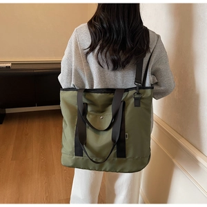 Olive green large capacity canvas tote bag worn by model showing casual side profile style