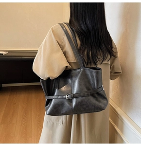 Schwarze Shopper-Tasche aus PU-Leder mit Zierschnalle lässig an der Schulter getragen