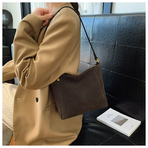 Detail of dark brown suede shoulder bag with zipper closure and slim black strap