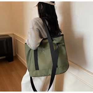 Detailed side view of military green canvas tote bag with adjustable black shoulder strap