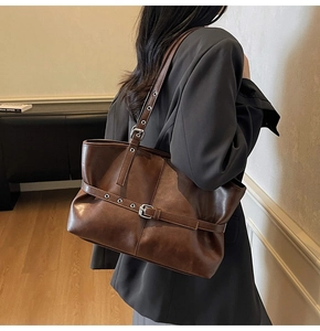 Seitenansicht dunkelbraune Leder-Tote-Bag mit silbernen Schnallenriemen an einem Model