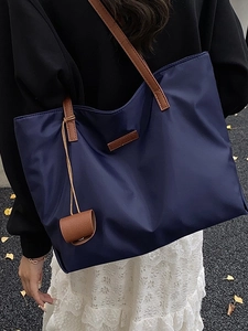 Grande borsa tote blu navy con manici in pelle marrone indossata da modella in autunno