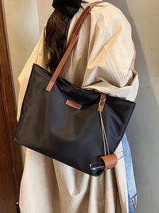 Grande borsa tote nera minimalista con manici in pelle marrone e logo del marchio
