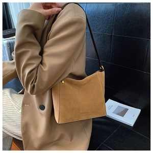 Detail of camel suede shoulder bag featuring brand logo and metal zipper closure