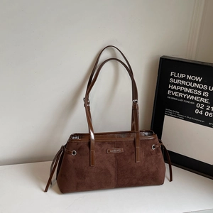 Detail of coffee brown suede handbag with metallic logo and striped lining