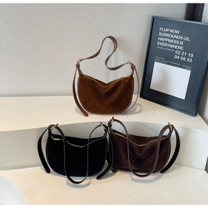Three suede crescent bags in caramel, black and coffee on minimalist display