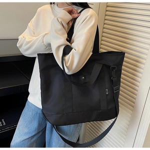Close-up of black nylon tote bag showing metallic hook detail and durable canvas texture