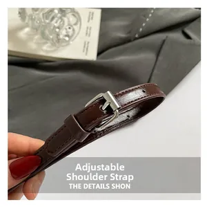Detail of adjustable dark brown glossy leather shoulder strap with silver buckle hardware