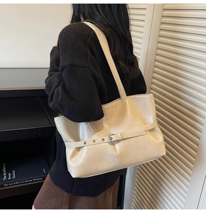 Detail der beigen Shopper-Tasche aus Kunstleder mit Metallschnalle und Schultergurt