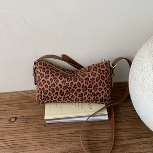 Détail d'un sac bandoulière léopard vintage sur bois avec bandoulière en cuir marron