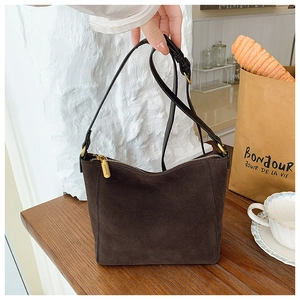 Macro shot of dark brown suede bucket bag with adjustable strap and metallic zipper detail
