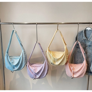 Detail of four colorful waffle texture half-moon crossbody bags on metal hangers