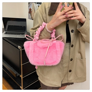 Detailed shot of pink plush handbag featuring ruffled handle and cute ribbon bow