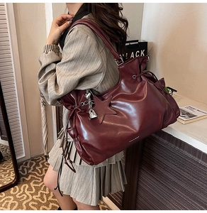 Détail du grand sac cabas bordeaux avec surpiqûres en étoile et breloques argentées