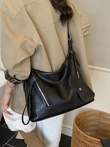 Black vintage hobo shoulder bag with metal zipper and heart charm on a female model