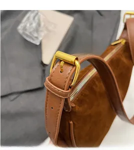 Detail shot of the golden metal buckle on the brown suede shoulder bag with leather strap
