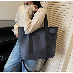 Detailed view of the large grey nylon tote bag with a detachable strap worn by a model