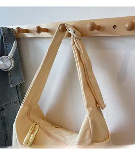 Close-up of beige waffle-textured crossbody bag with dual zippers and wide shoulder strap