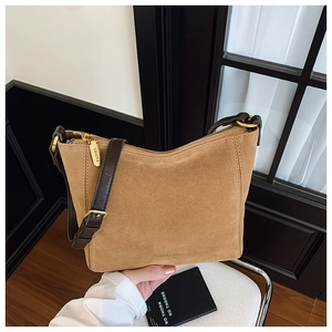 Detail of suede bucket bag showing golden zipper with engraved logo and leather strap