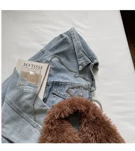 Detailansicht der braunen Lammfell-Tasche mit silberner Kette auf einer Denim-Jacke
