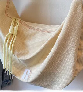Detail view of beige waffle fabric texture and knot zipper on dumpling crossbody bag
