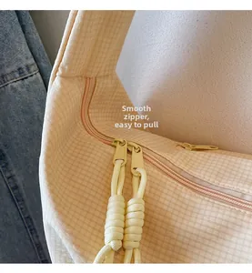 Close-up of dual smooth zippers with woven cord pulls on a yellow checkered tote bag