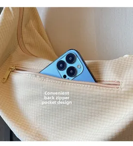 Close-up of the back zipper pocket on the beige checkered bag holding a smartphone