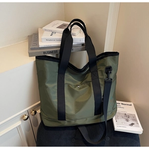 Detailed view of olive green nylon tote with reinforced black handles and adjustable strap