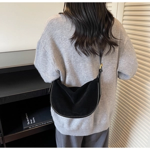 Detail of minimalist black crescent bag featuring soft suede texture and gold hardware