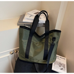 Detail of army green canvas tote with black straps and removable shoulder strap
