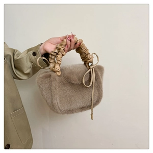 Detail of plush faux fur handbag with scrunchie style handle and soft hanging ribbons
