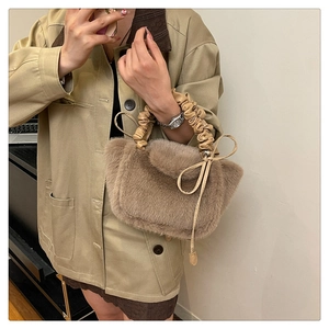 Macro detail of the plush brown faux fur texture and elegant drawstring bow on the handbag