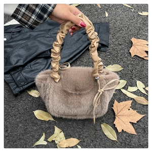 Detail of plush faux fur tote bag with ruched leather handle and bow decoration