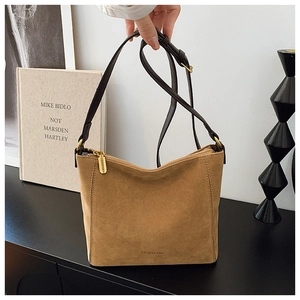 Detail of suede bucket bag showing fine texture and golden metal hardware adjustment buckle