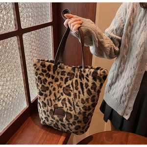 Detail of leopard print plush bucket bag with brown leather handles in a warm winter setting